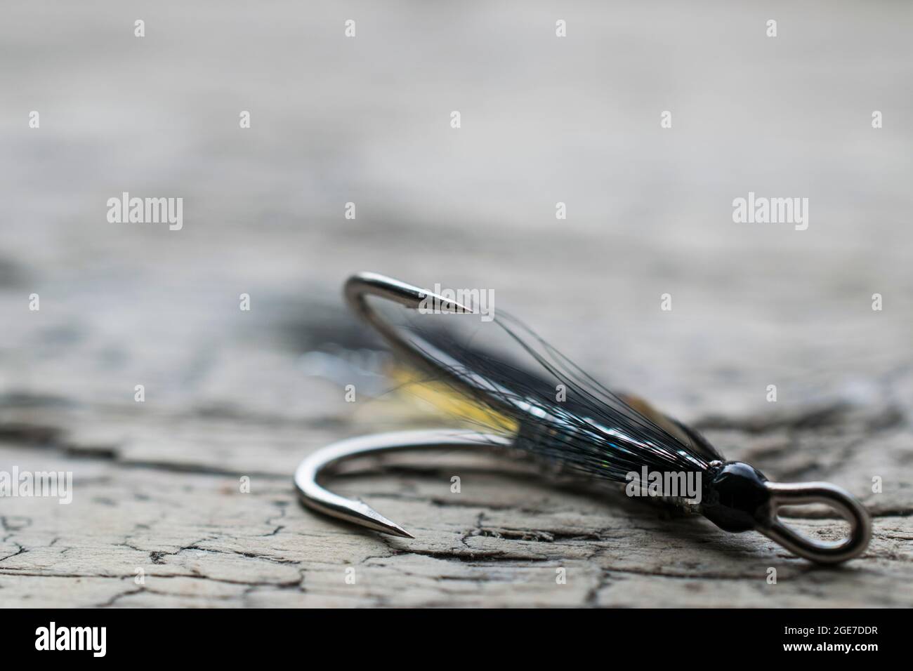 Shiny salmon fishing fly with yellow flash on a wood surface Stock Photo