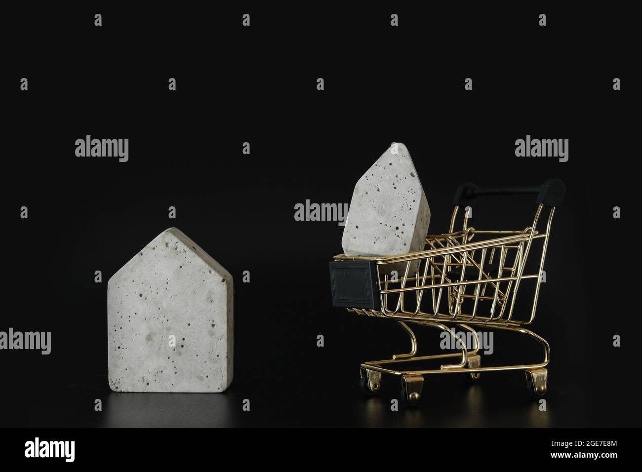 Buy or rent, choice. House model in mini shopping cart on the black background. Buy a house. Concept for property ladder, mortgage and real estate inv Stock Photo