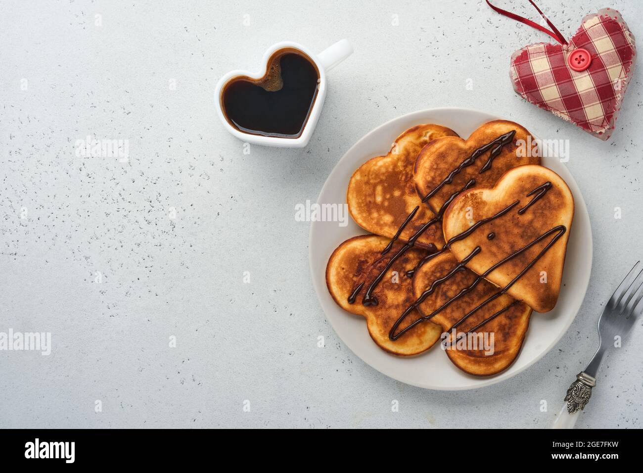 Pancakes in shape of breakfast hearts with chocolate sauce in gray ceramic plate cup of coffee on gray concrete background. Table setting for your fav Stock Photo