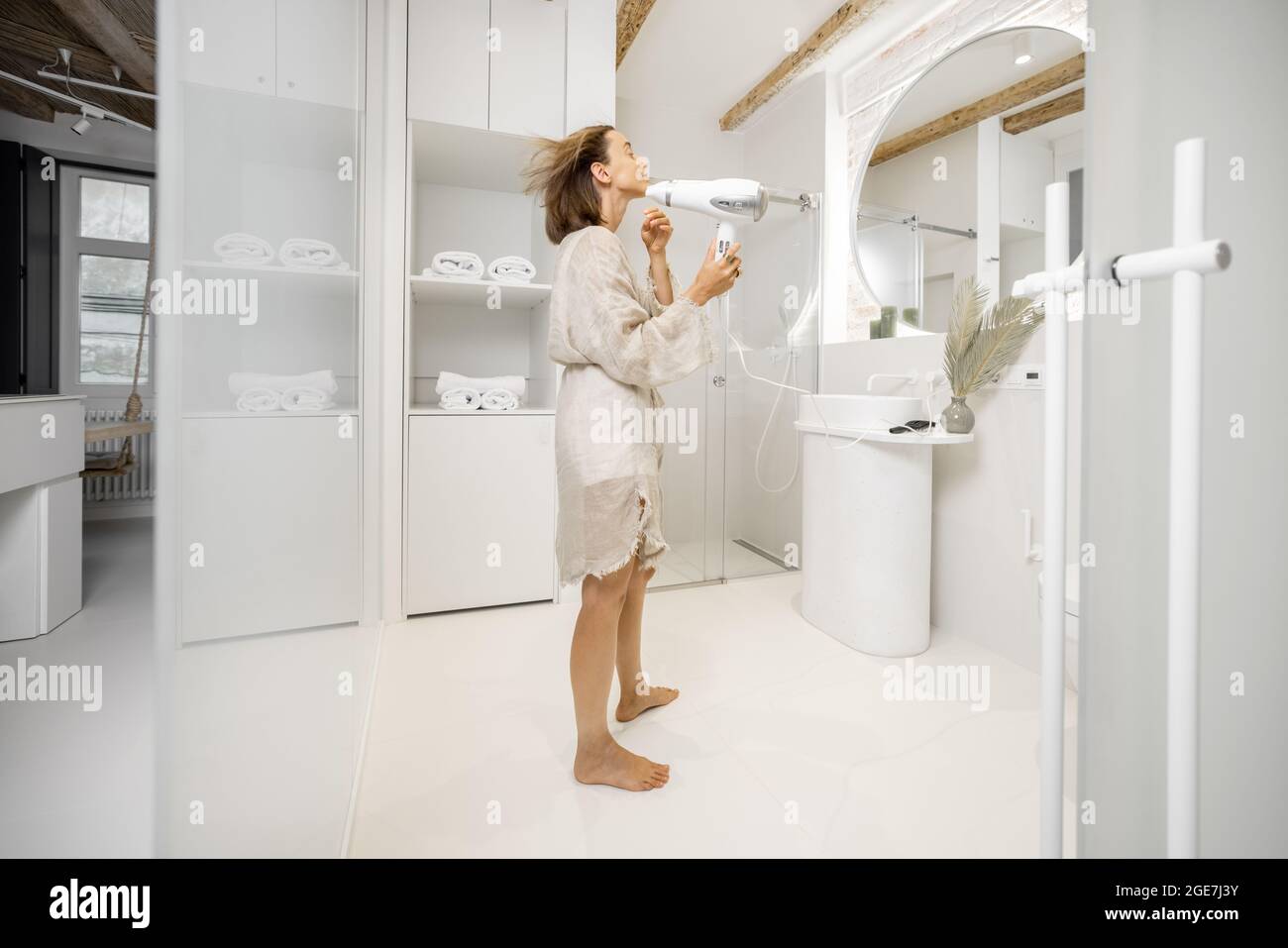Woman dries hair with a hair dryer in a modern bathroom Stock Photo - Alamy