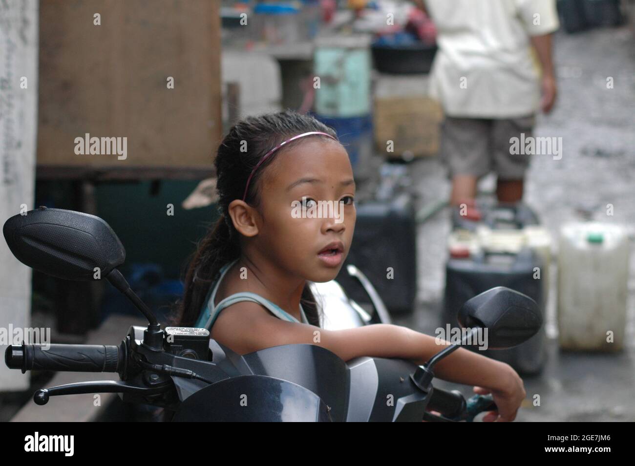 MANILA, PHILIPPINES - Oct 20, 2011: A Filipino young girl with a surprised look sitting in a village in Manila, Philippines Stock Photo