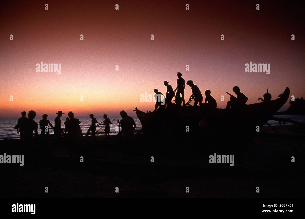 Fishermen pulling nets at dusk, Baga Beach, Goa, India Stock Photo