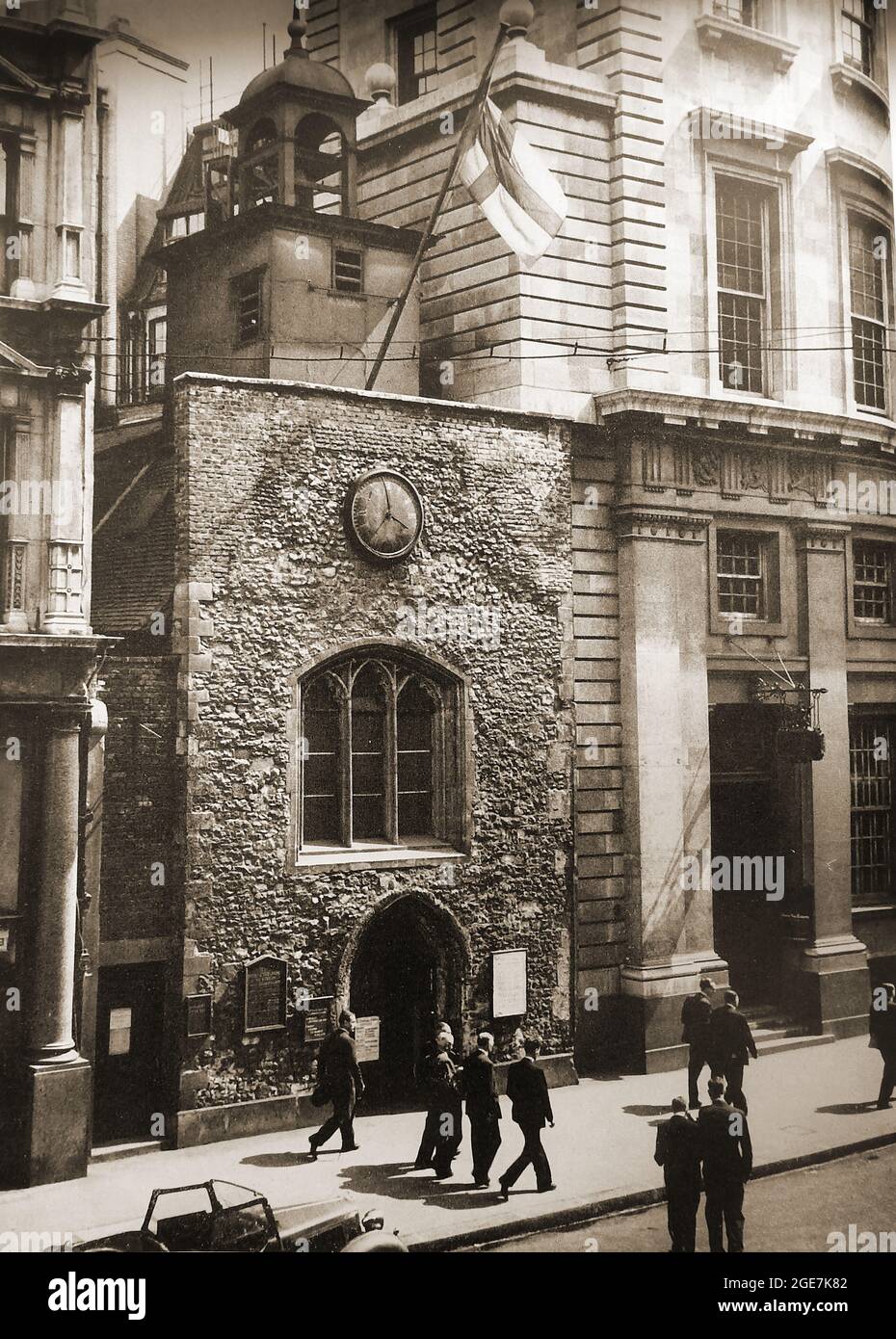 St Ethelburga's Church, Bishopgate, London, UK as it was in the late 1940's before restoration to its present form. Fully known as St Ethelburga-the-Virgin within Bishopsgate. It was bombed by the IRA (Irish Republican Army)  & has since been restored. It survived the Great Fire of London (1666 ) & is is dedicated to St Ethelburga (Adelburga ) 7th-century abbess of Barking Abbey. it has undergone a number of changes including rebuilding in the 15th century & the addition of a small square bell turret in 1775, a weathervane  in 1671 and a wooden front porch containing 2 shops (pulled down1938). Stock Photo