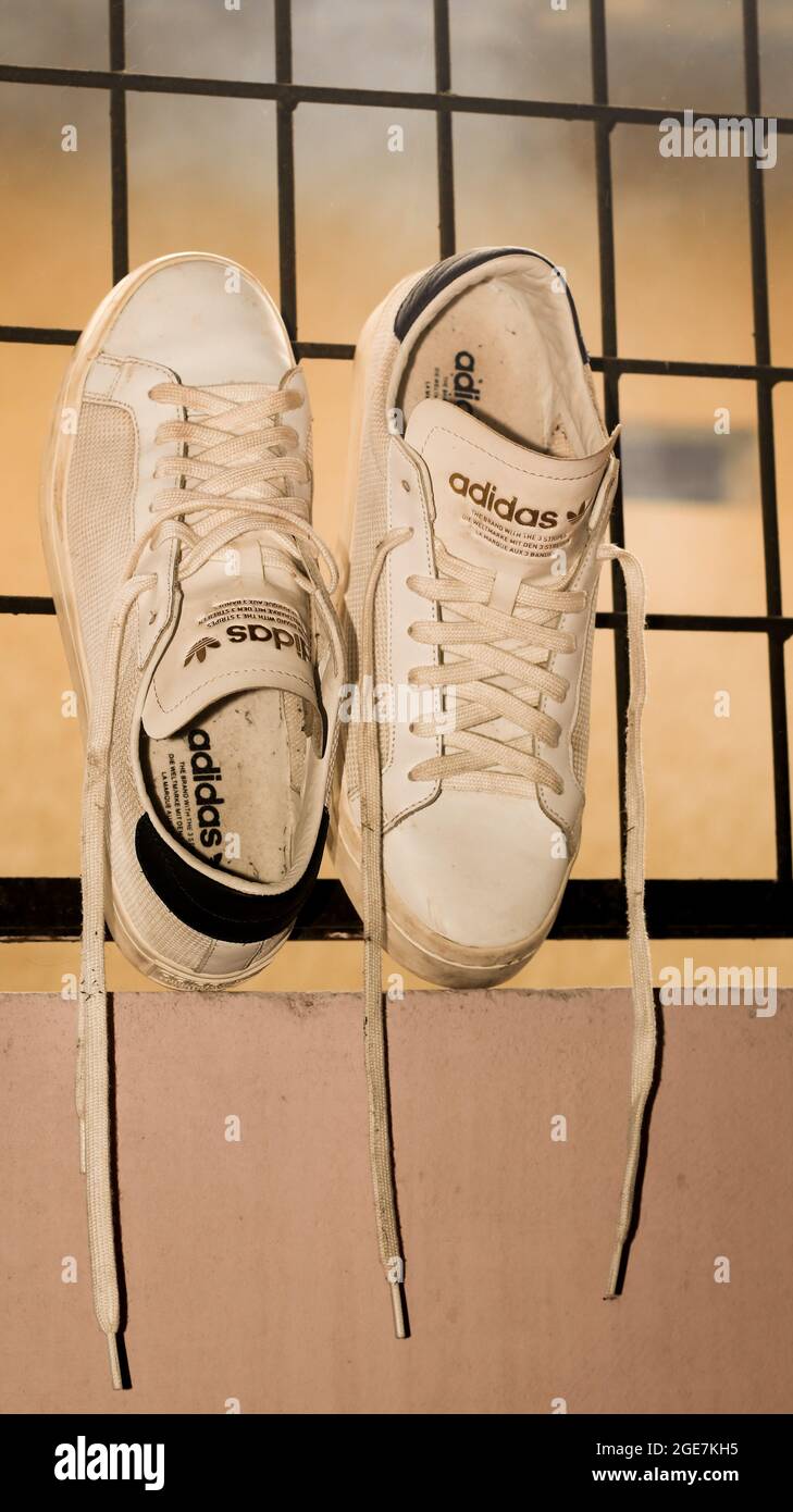 MUMBAI, INDIA - Aug 14, 2019: Fashionable white and gold Adidas originals  Stansmith shoes full of dust kept leaning to the grilles Stock Photo - Alamy