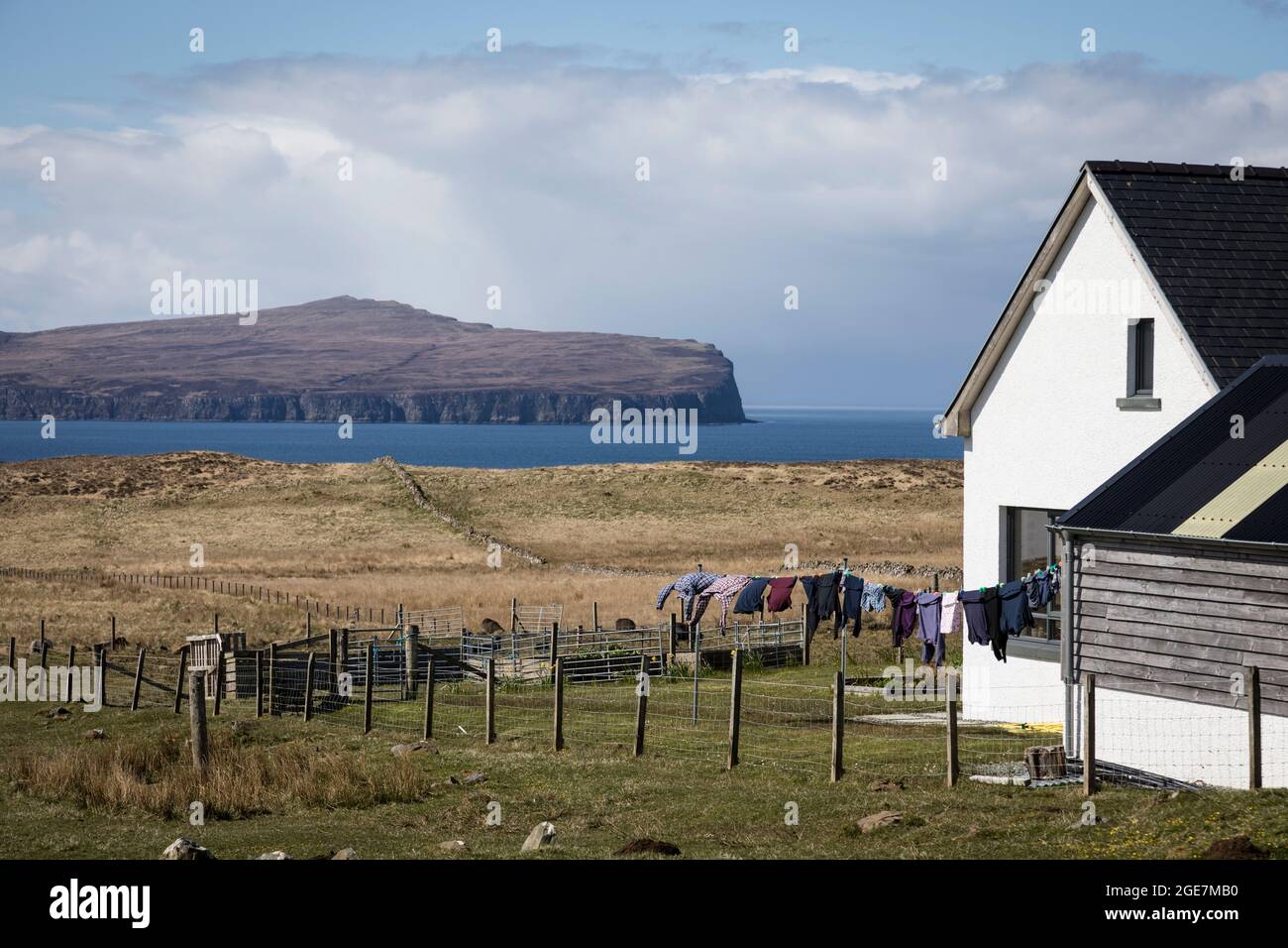 Remote house with line full of washing drying in the breeze with sea and hills beyond, Waternish, Isle of Skye, Scotland. Stock Photo