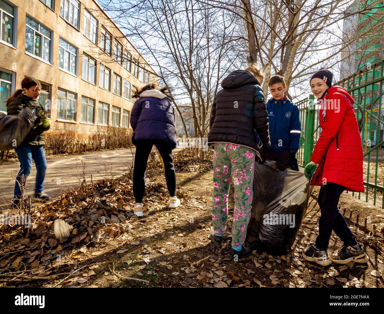 Omsk, Russia. 24 April, 2021. Schoolchildren carry the leaf litter bag