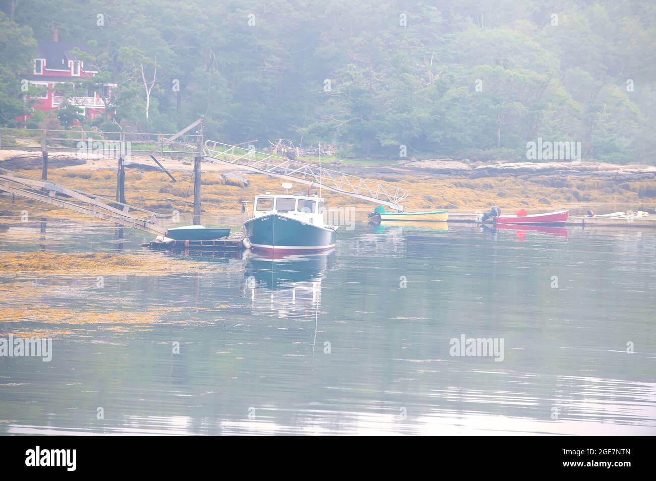 Lobster boats await the lifting of an early morning fog in East Boothbay, Maine, USA Stock Photo