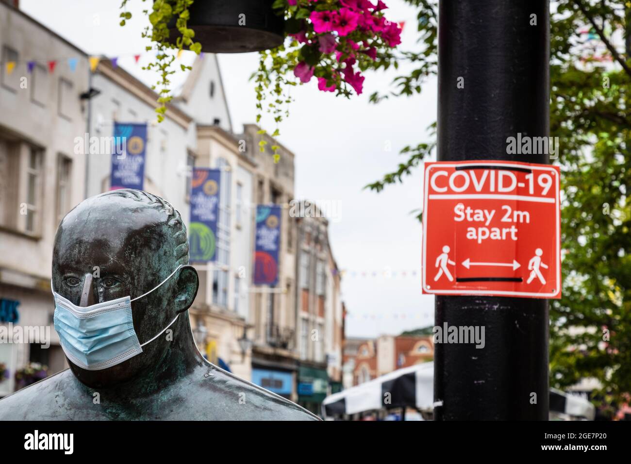 'The Sockman' by Scottish artist Shona Kinloch represents Loughborough's hosiery industry and seen here with a face mask alongside a Covid sign Stock Photo