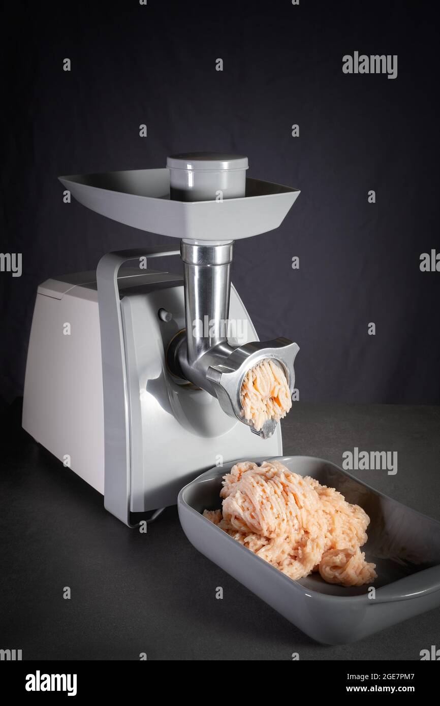 Electric meat grinder works and twists raw minced meat in the kitchen