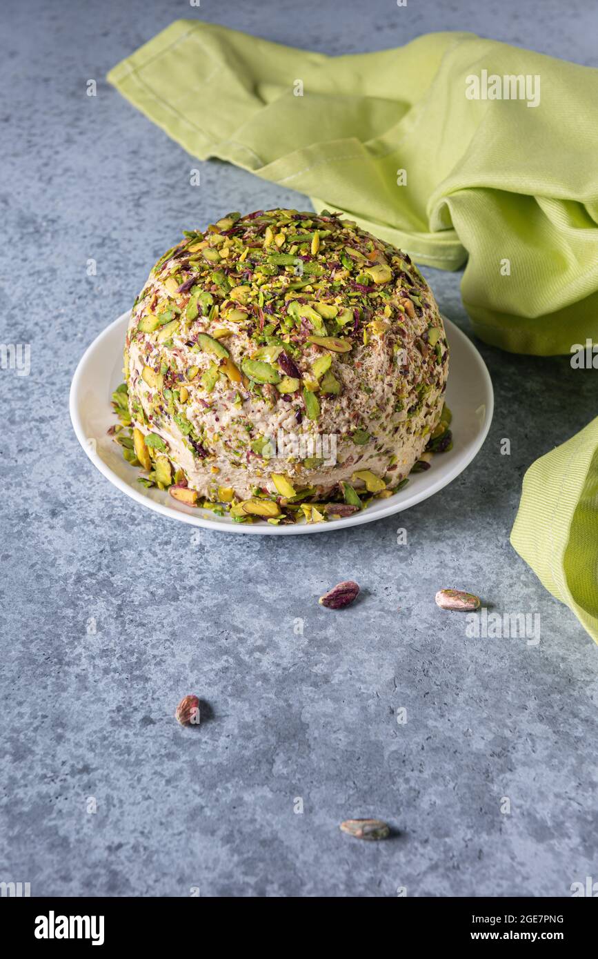 Halva with pistachios, few scattered nuts, green linen napkin and large copy space. Traditional middle eastern sweets. Jewish, turkish, arabic dessert Stock Photo