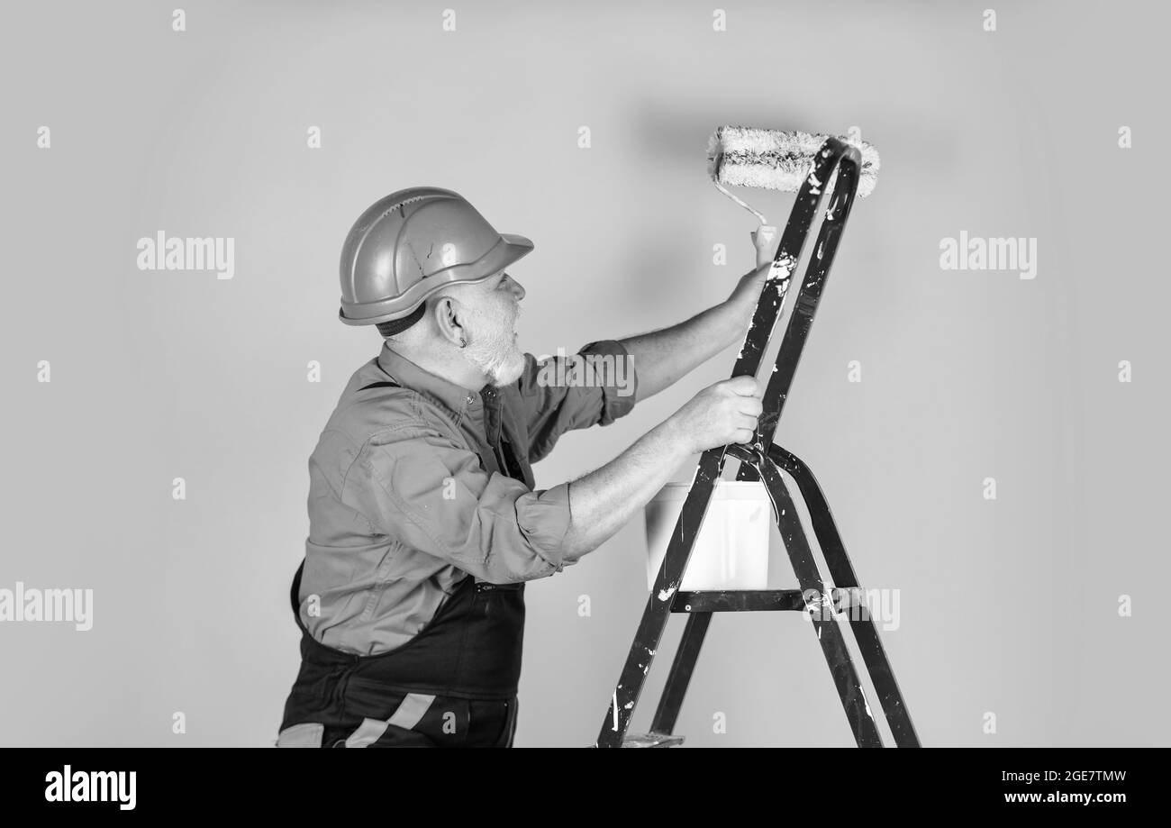 To make repairs. man in working clothes painting wall in empty room