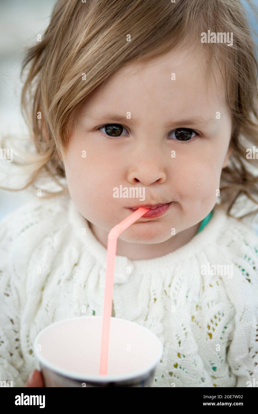 Cute little girl drinking milk using drinking straw Stock Photo