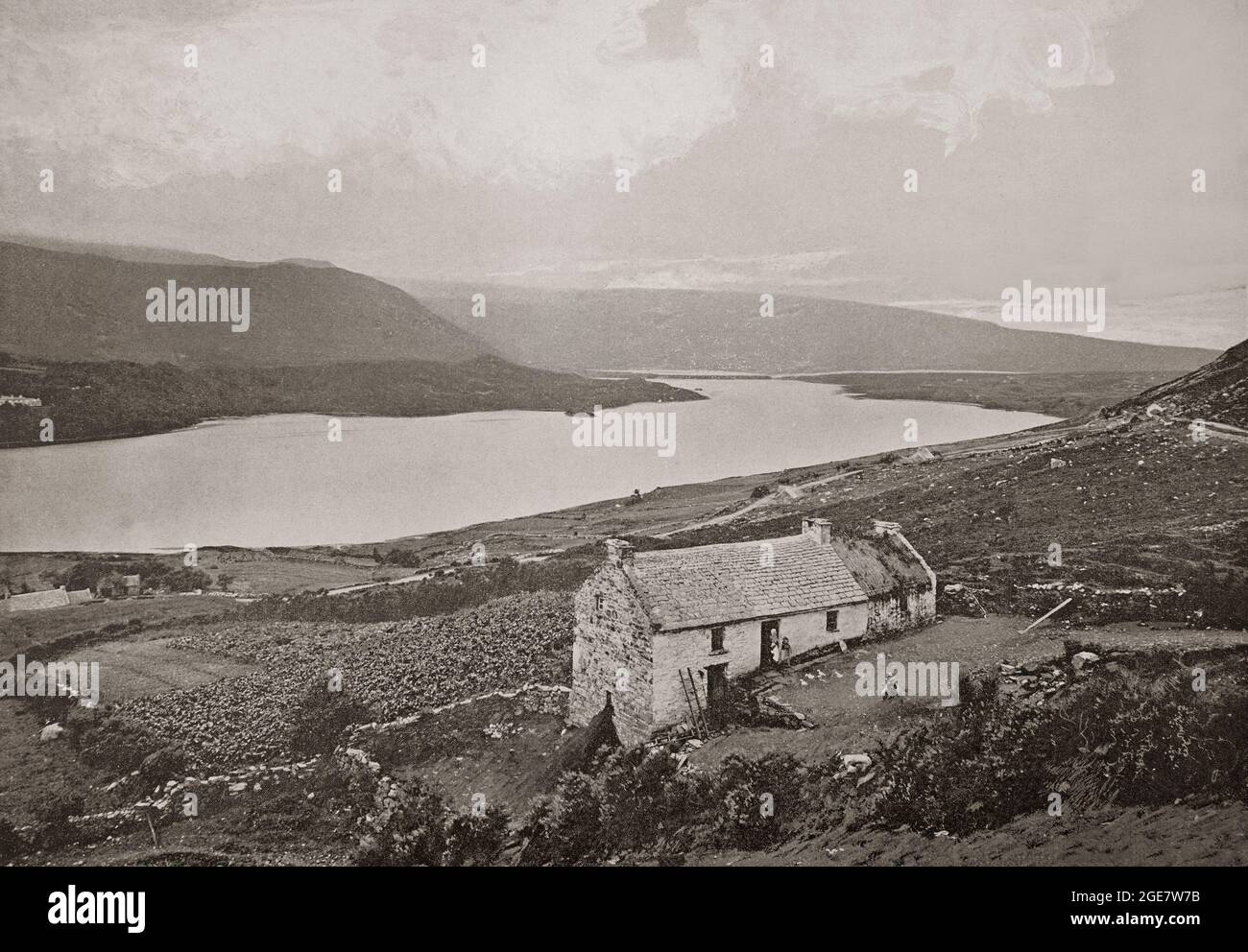 A late 19th century view of Dunlewey Lough, or Dunlewy Lough, in County Donegal, Ireland. It lies at the foot of Errigal and beside the hamlet of Dunlewey (or Dunlewy). Long settled, there's the remains of a crannóg (a fortified lake dwelling) on the lake, which  may be the source of the name Dún Lúiche, which means 'Lugh's fort'. Stock Photo