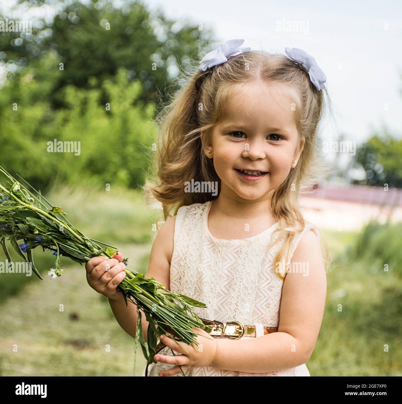 happy little girl smiling and holding a bouquet of wildflowers Stock ...