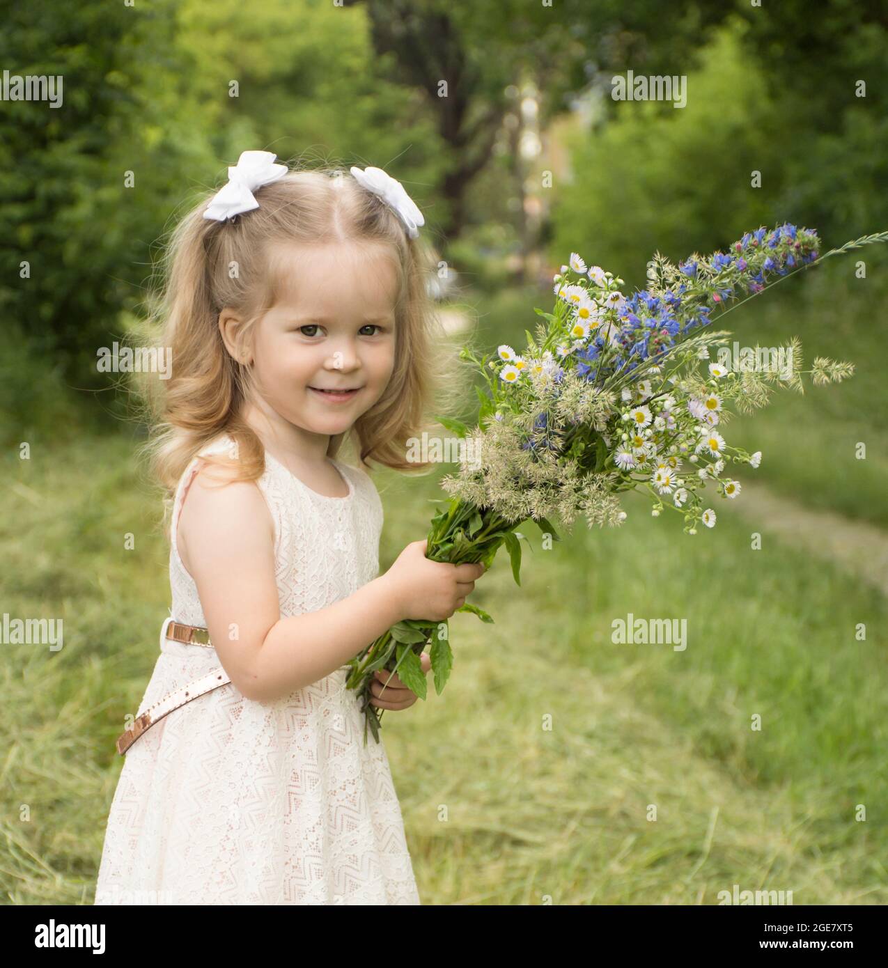 beautiful happy little girl with a bouquet of wildflowers in her hands ...