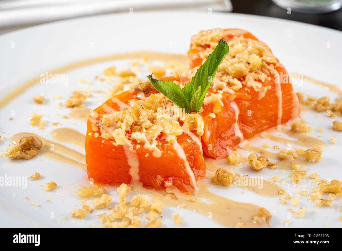 Pumpkin dessert with tahini and walnuts on a white porcelain plate Stock Photo