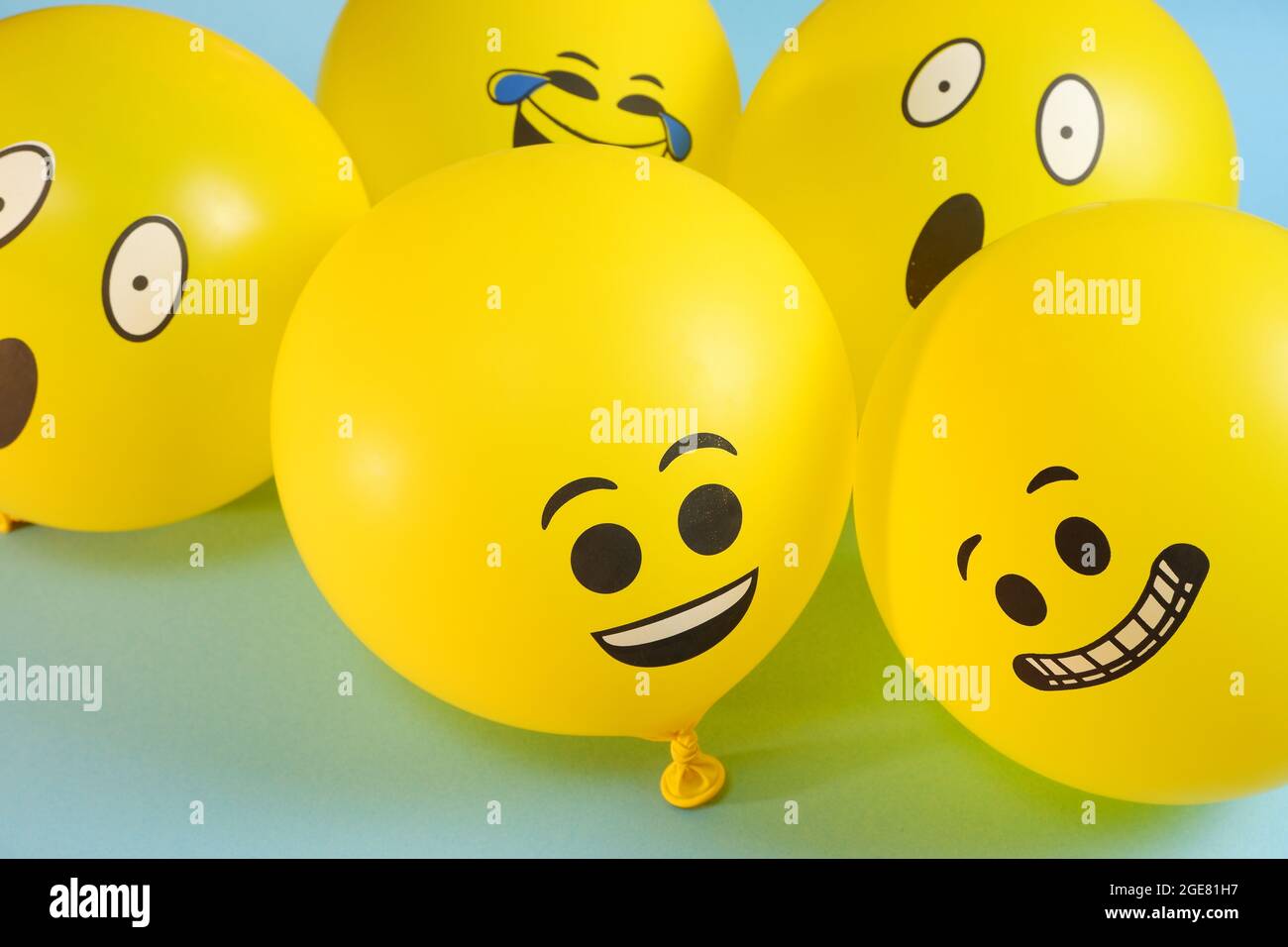 Yellow emoji balloons on a blue background. Stock Photo