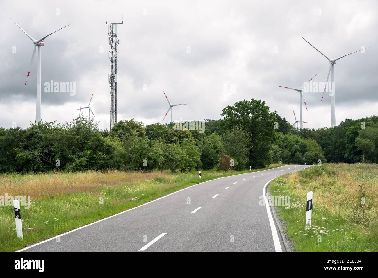 Deserted country road running through a wind farm on a cloudy summer day Stock Photo