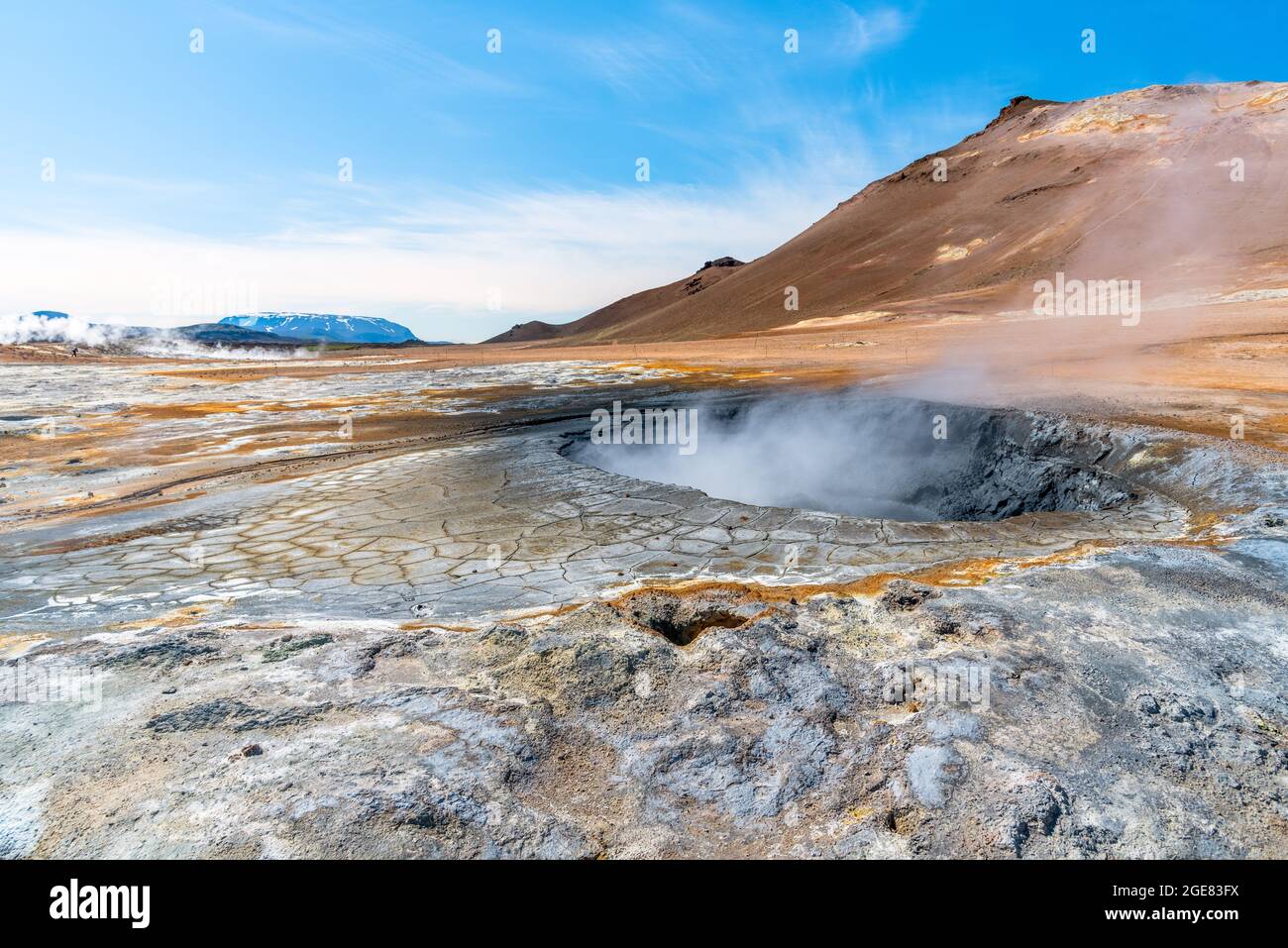 Steaming mud pot in a geothermal area on a sunny summer day Stock Photo