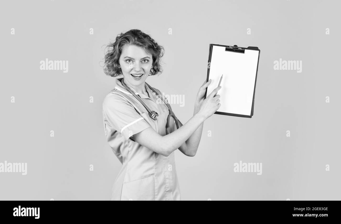 look here. therapist in uniform at hospital. medical history and prescription. Professional doctor holding folder. happy young nurse holding clipboard Stock Photo