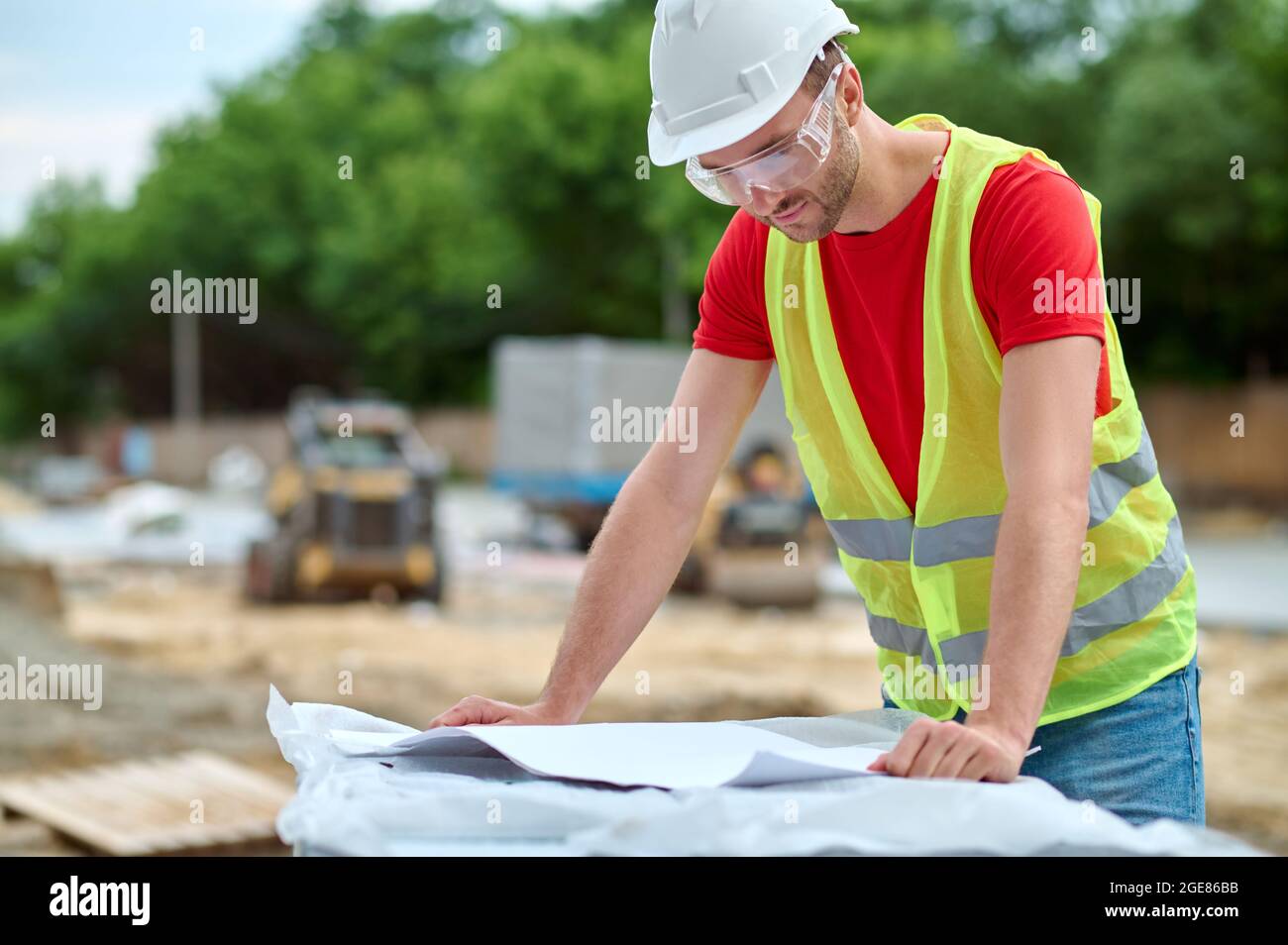Worker in protective eyewear leaning over a technical drawing Stock Photo