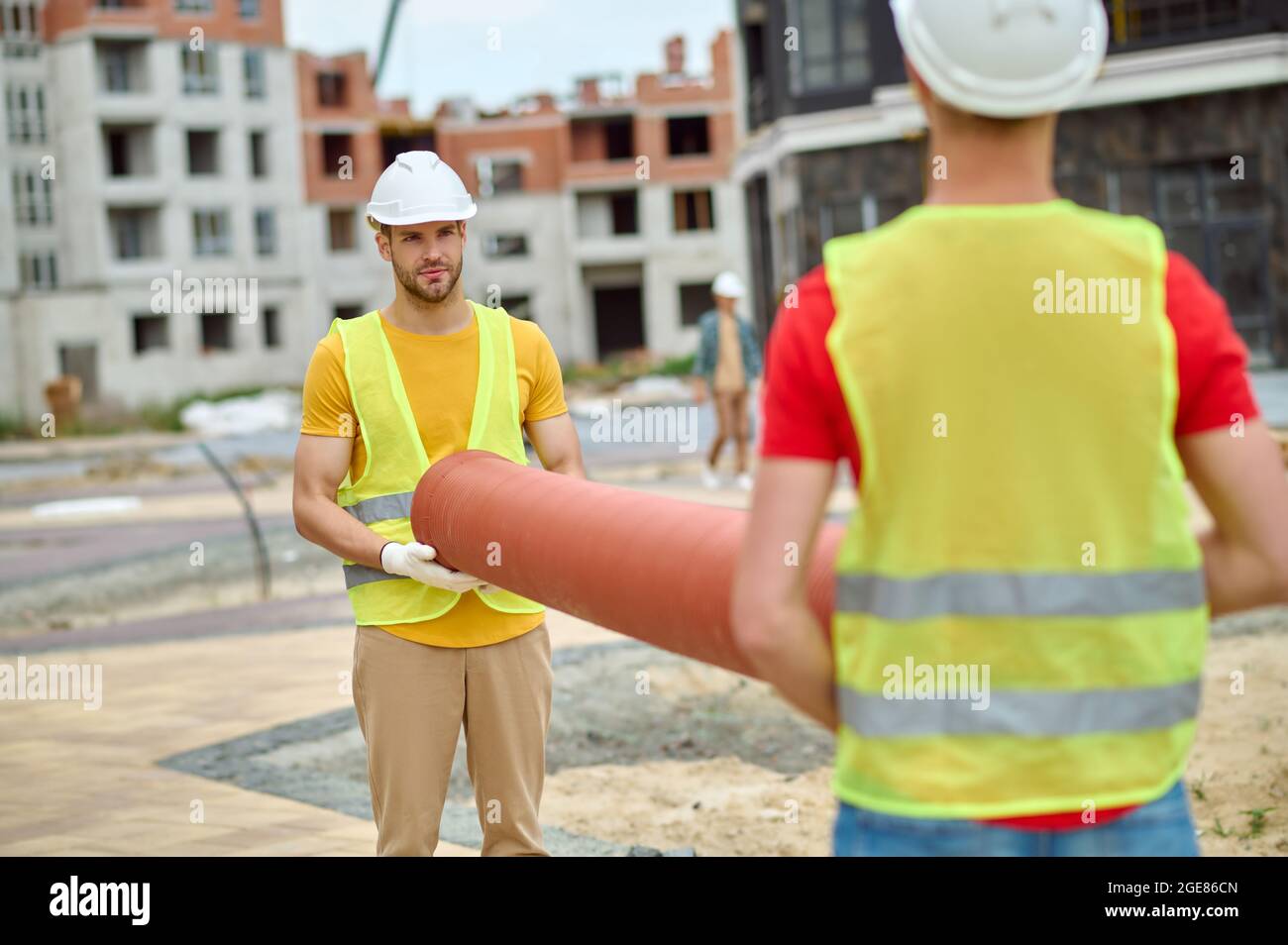 Two construction workers in reflective waistcoats and hardhats working outdoors Stock Photo