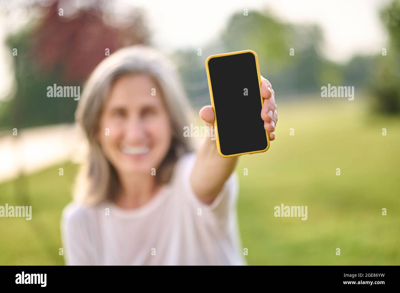 Smartphone in outstretched hand of smiling woman Stock Photo