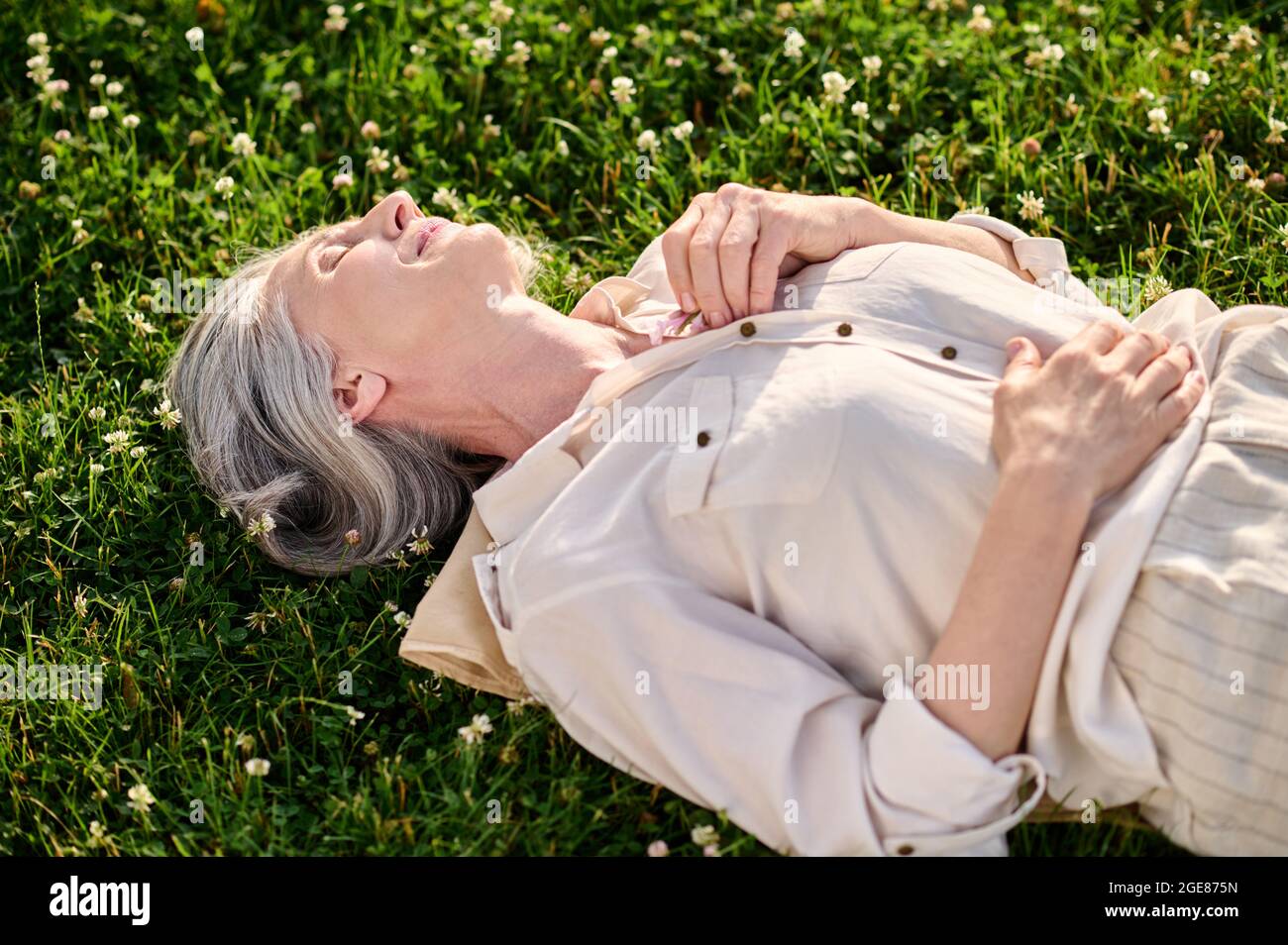 Woman lying dozing on green lawn Stock Photo