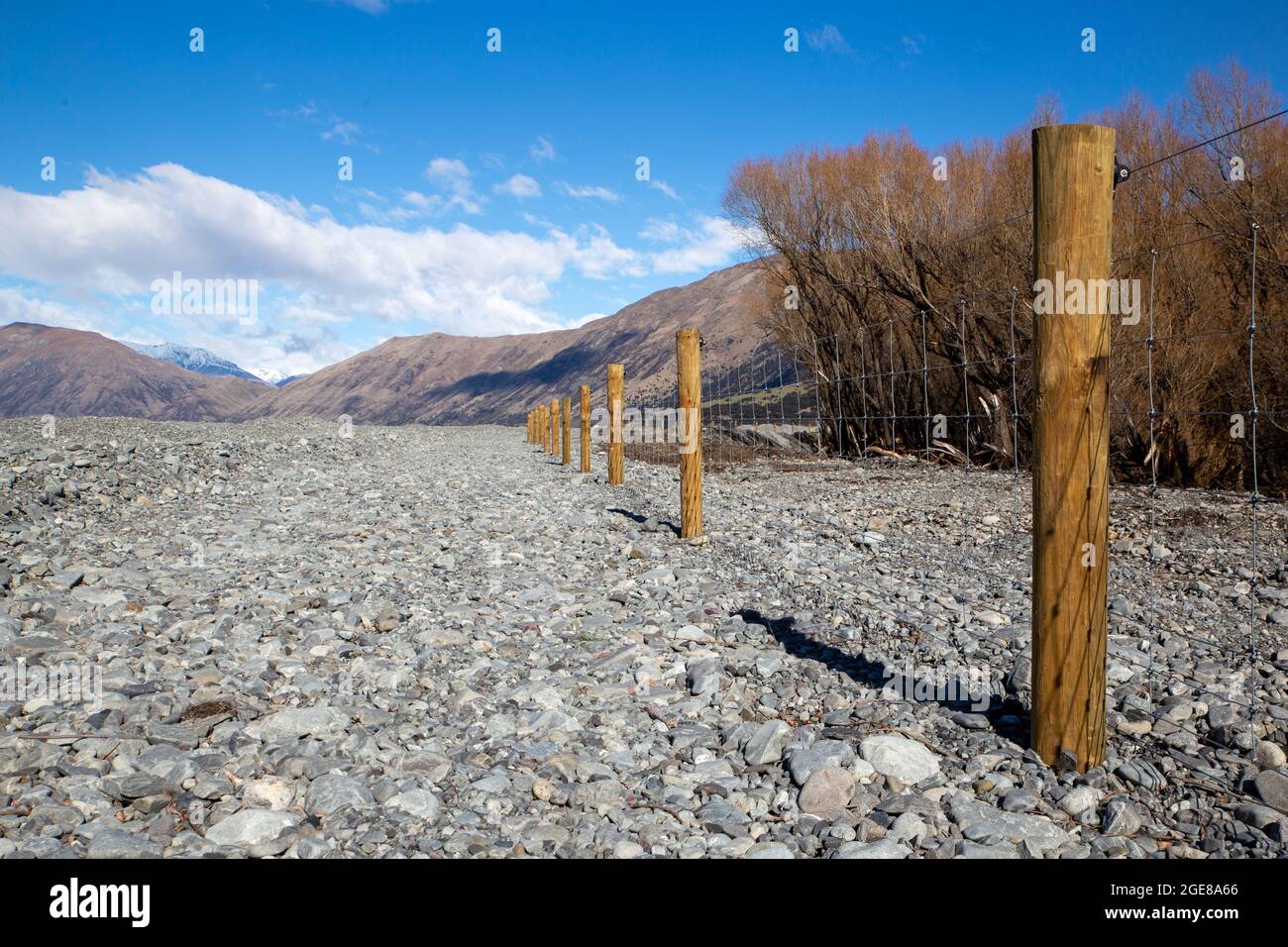 New post and netting fence dividing the farm boundary from the river bed  in the high country, Canterbury, New Zealand Stock Photo