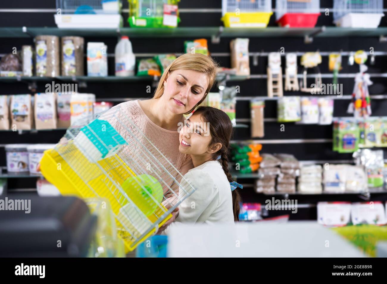 Smiling woman with her daughter choosing hamster cage Stock Photo