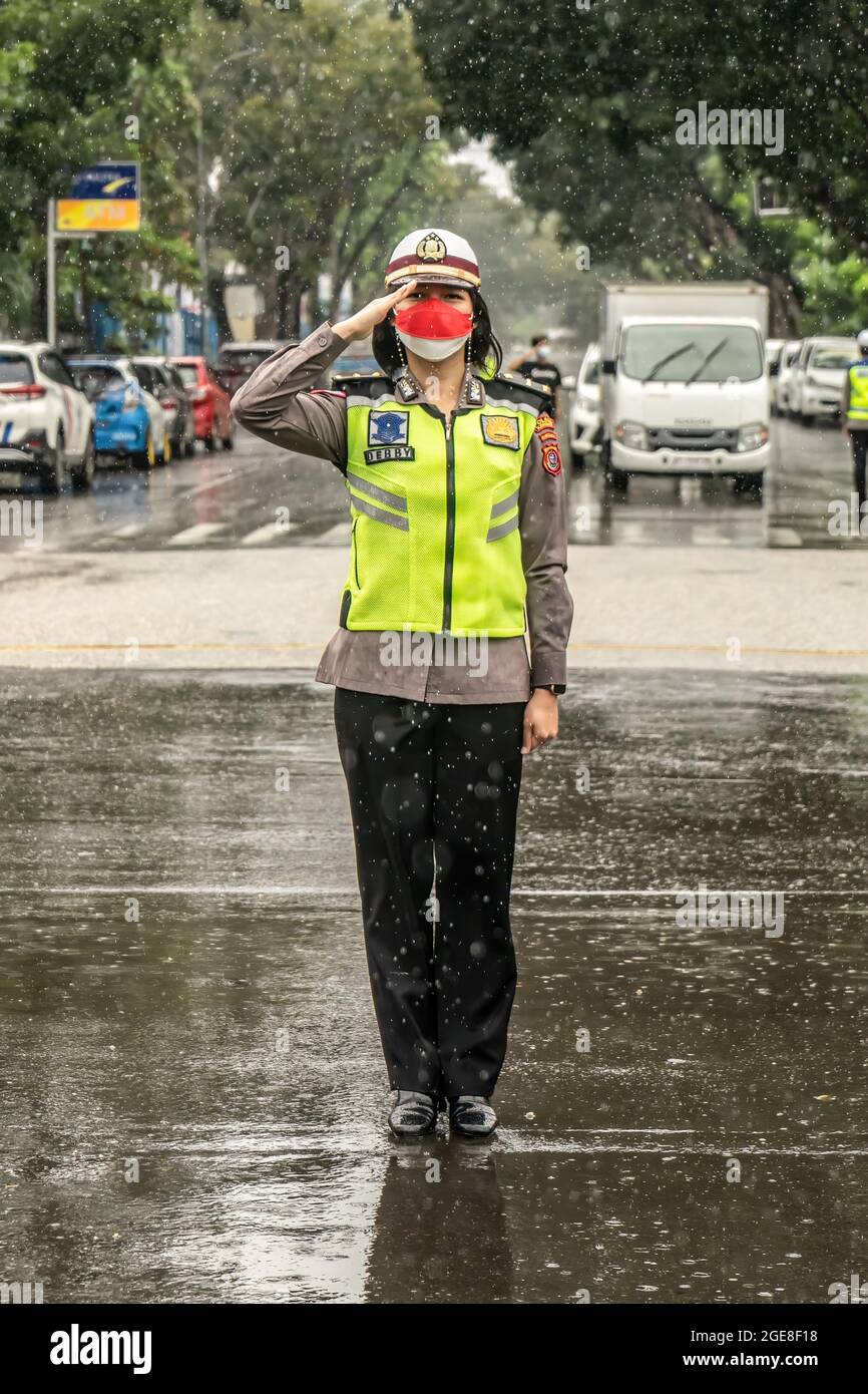 A policewoman with impeccable demeanor pays homage during a  downpour.Members of Kendari resort traffic police unit stopped motorists  passing at the intersection of the Kendari mayor's office at 11.17 a.m.  WITA (