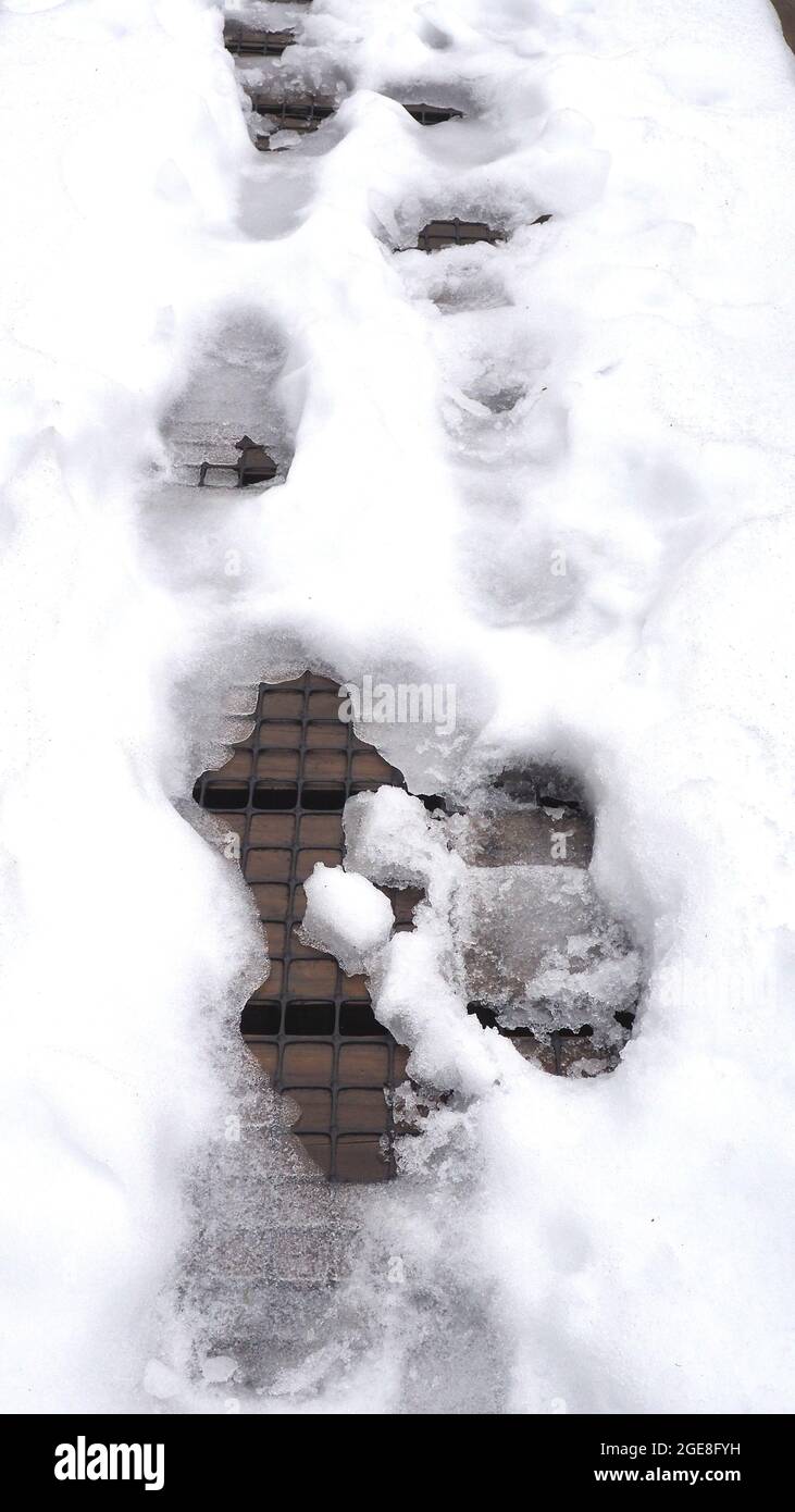 Boot footprints in snow on a wooden bridge covered in plastic safety mesh to prevent slipping. The Wilkies Pools walk, Egmont National Park, NZ. Stock Photo