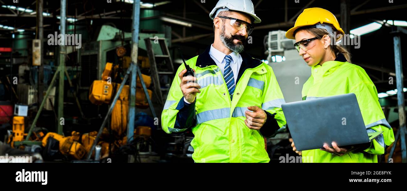 Diversity factory worker working with computer, Industrial Engineer in the hard hat uses laptop computer while standing in the heavy industry manufact Stock Photo