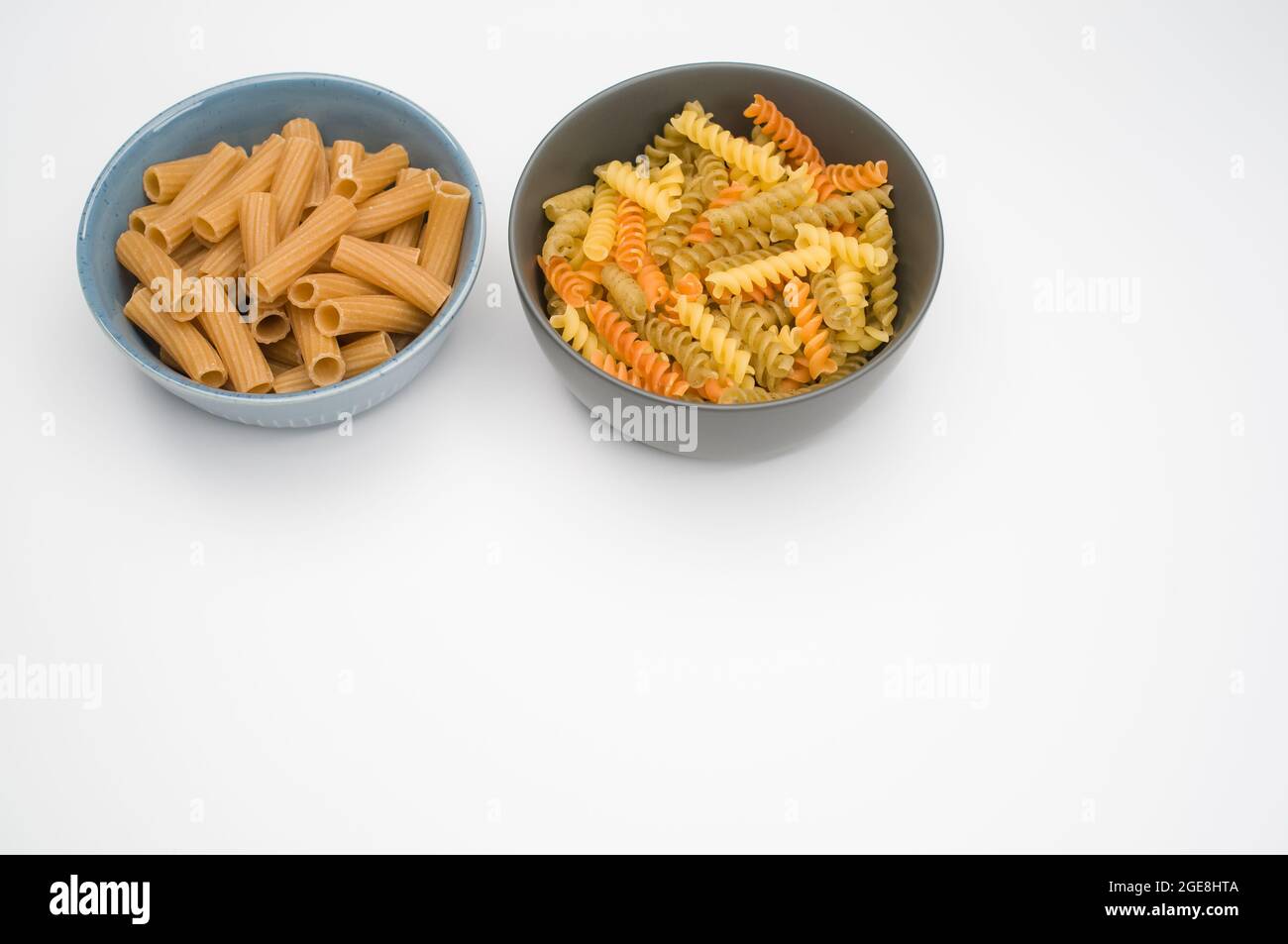 High angle of tricolor rotini and rigatoni pasta on a bowl isolated on