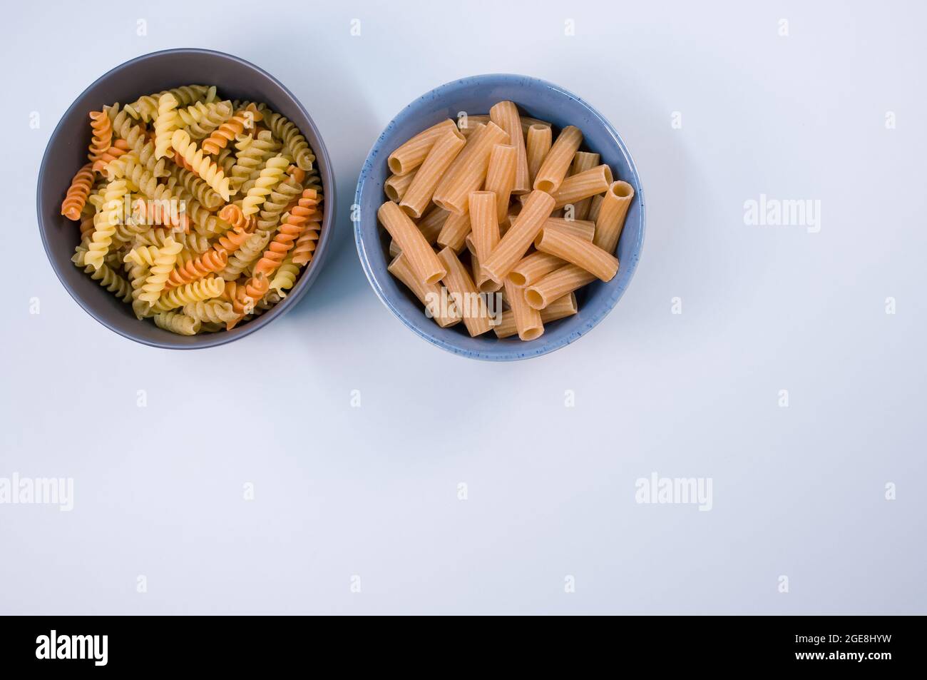 Top view of tri-color rotini and rigatoni pasta on bowls isolated on ...