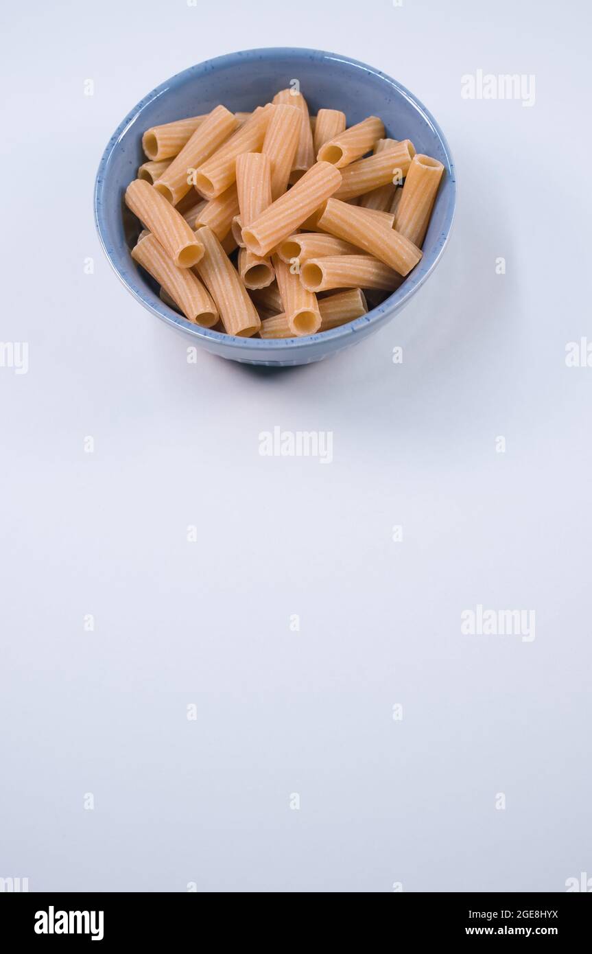 Vertical shot of uncooked rigatoni pasta on a bowl isolated on white ...