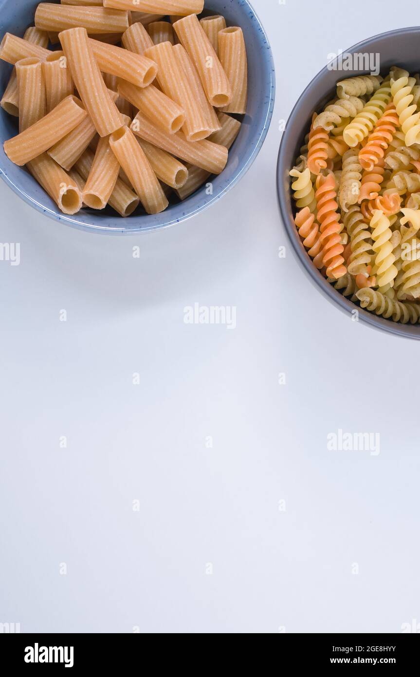 Vertical shot of tricolor rotini and rigatoni pasta on a bowl isolated