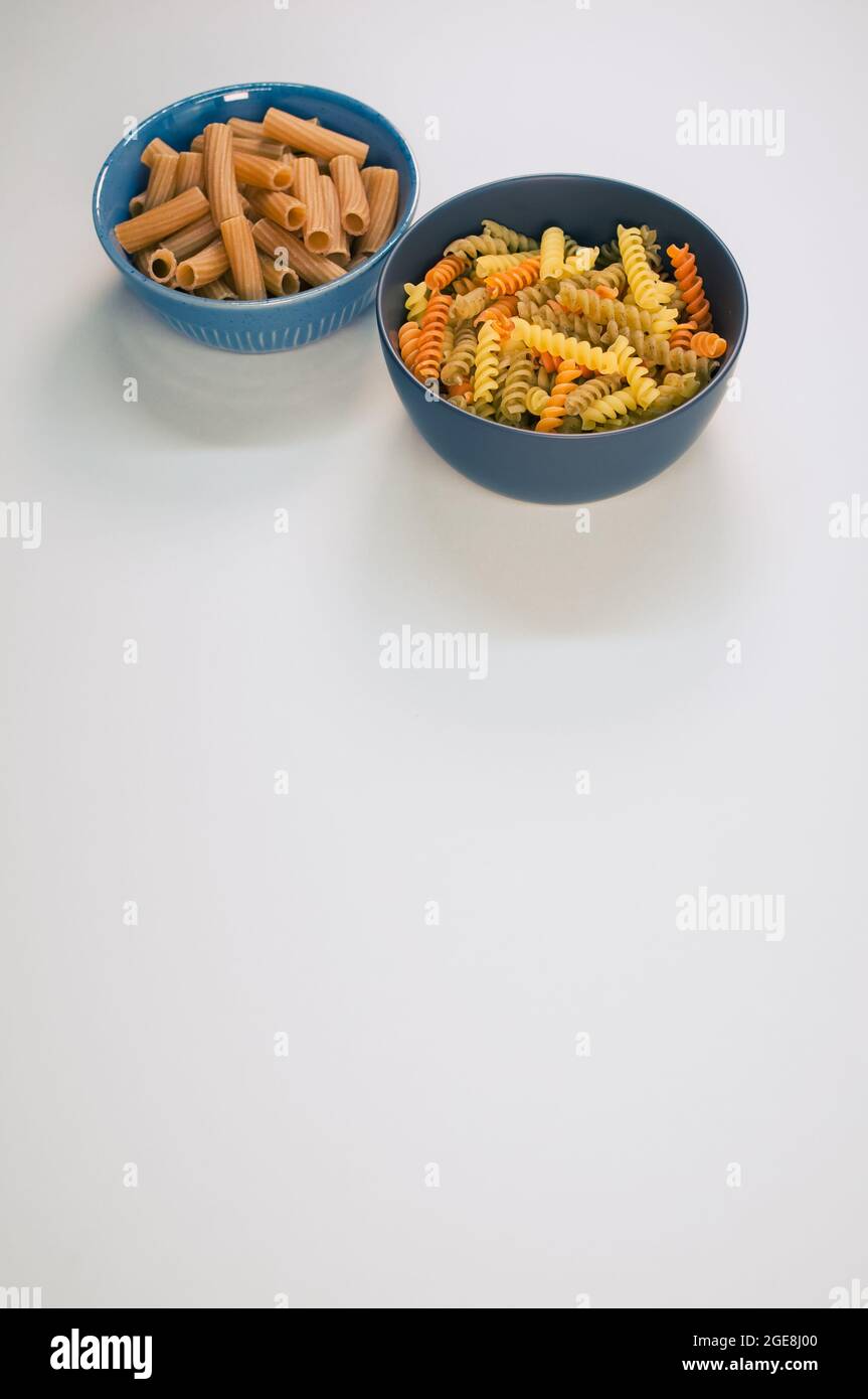 Vertical shot of tri-color rotini and rigatoni pasta on a bowl isolated ...