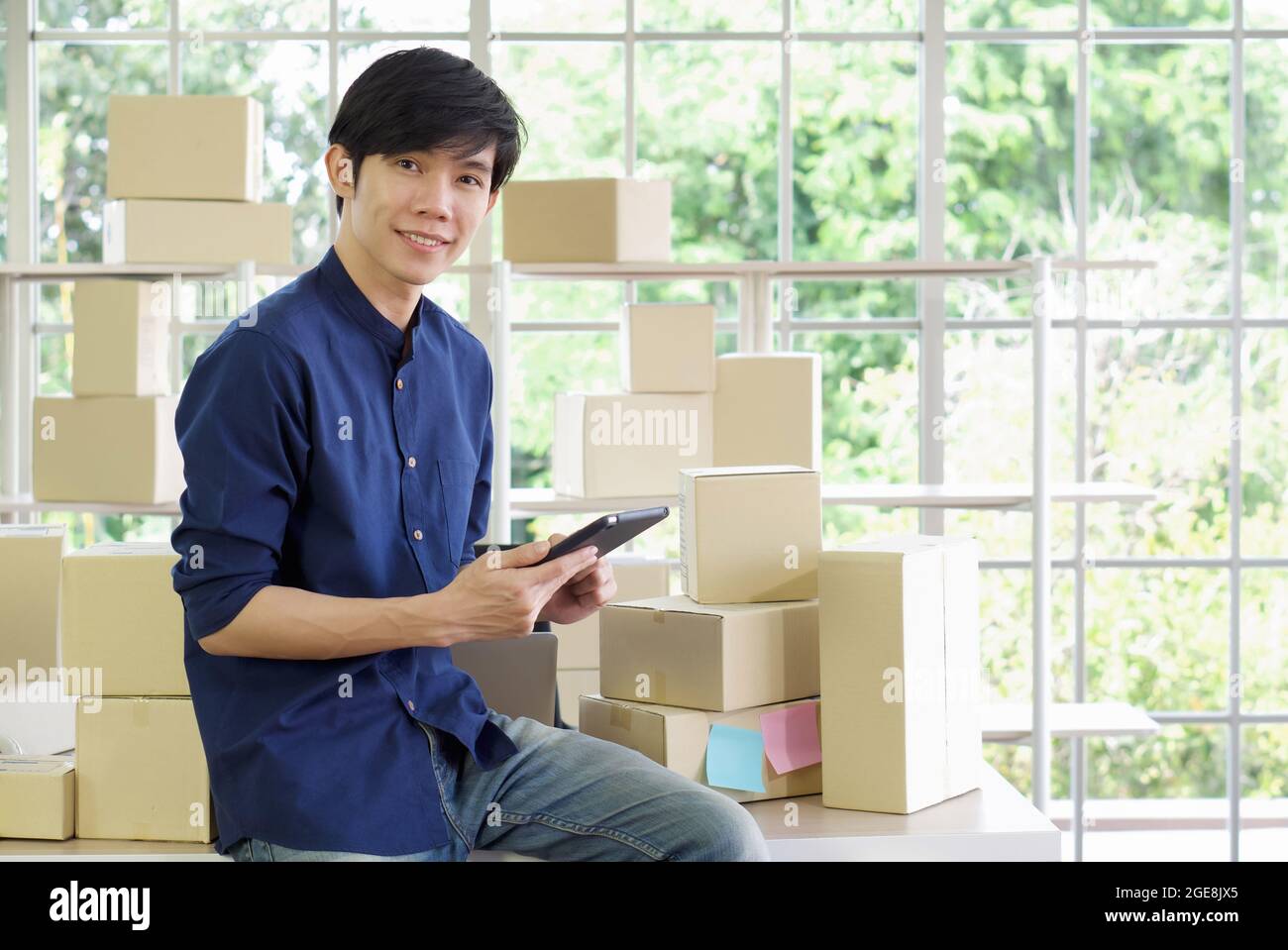 Young entrepreneur checking products stock with tablet computer at home office. Work from home concept. Stock Photo
