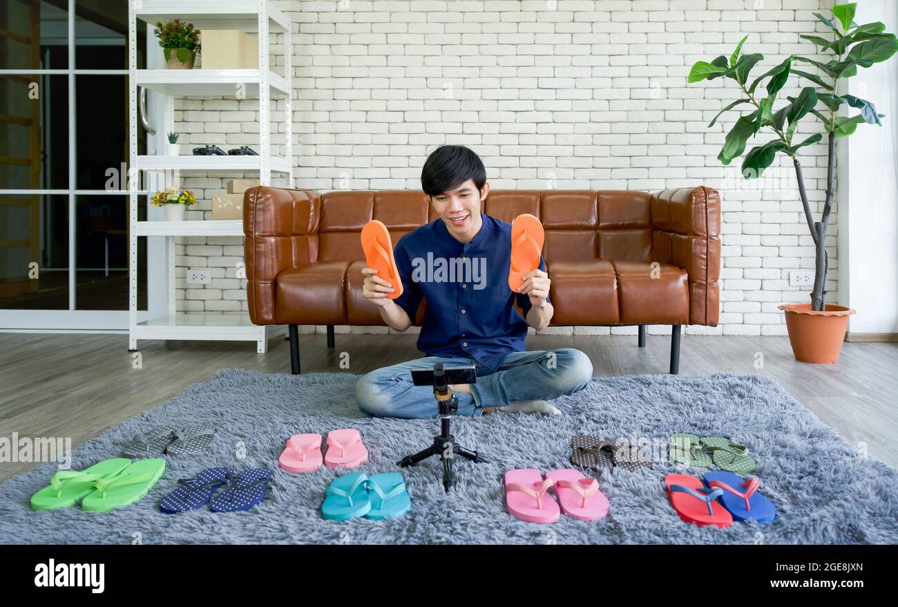 Young asian man sells various styles of rubber slippers online via  application on mobile phone. Small home business concept Stock Photo - Alamy