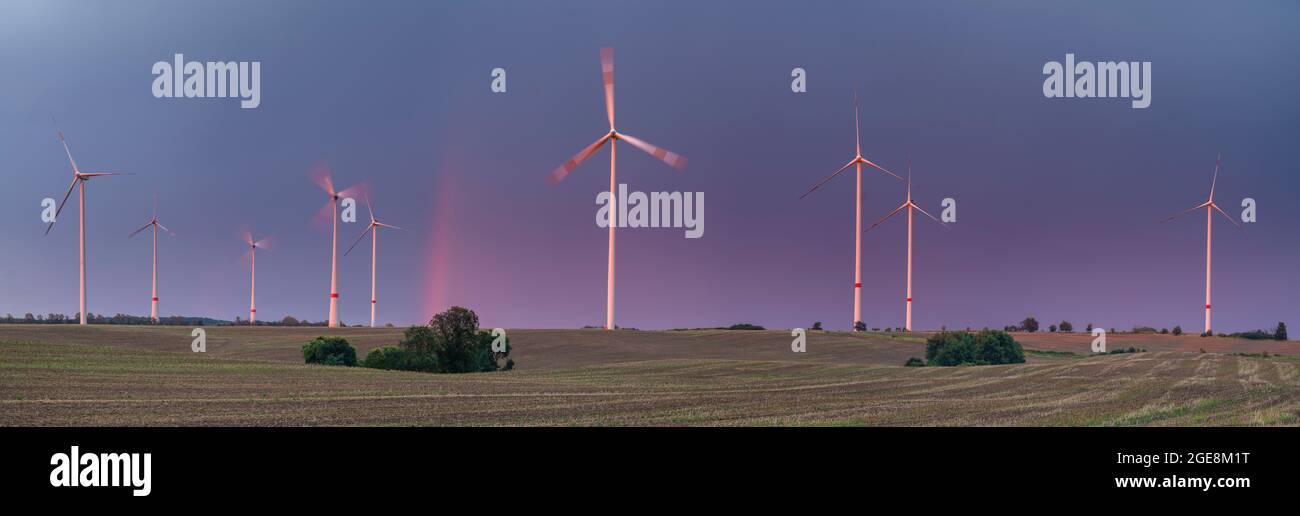Red rainbow after passing an evening storm over a farm windmills Stock Photo