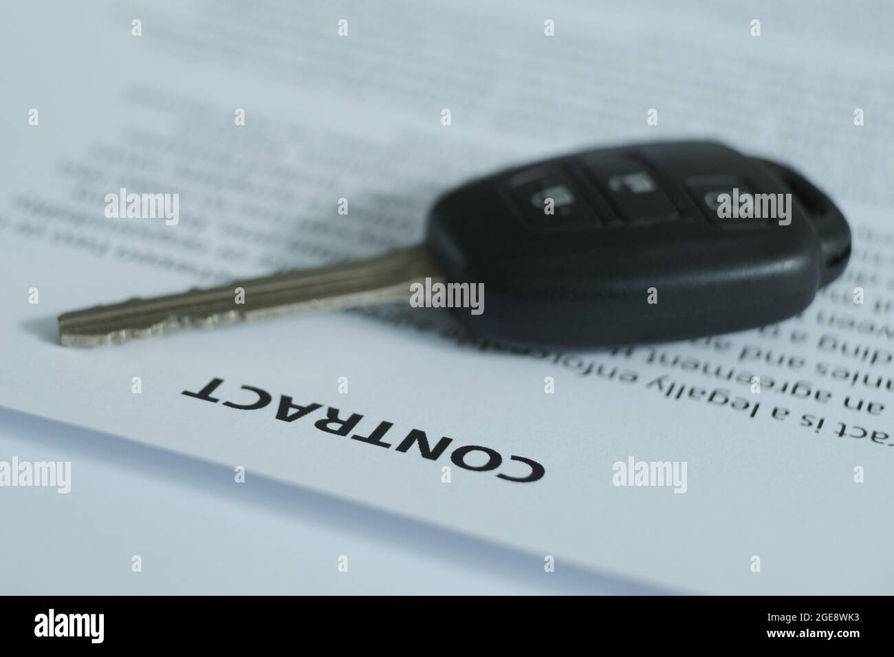There is a contract and car keys on the table, the emphasis is on the name of the document and the keys.  Blurred image. Stock Photo