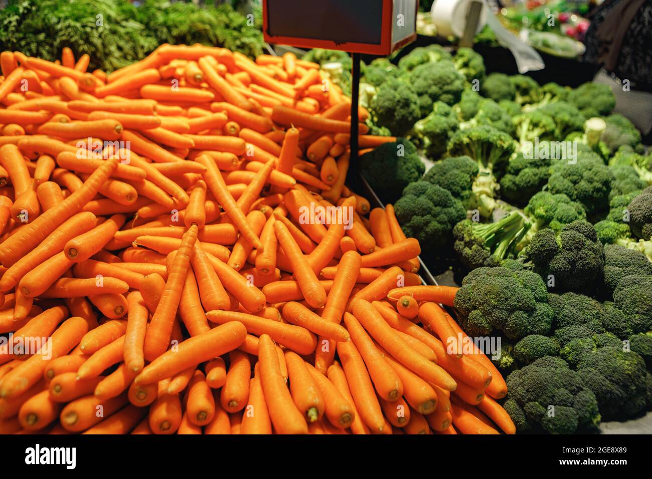 Pile of fresh carrots and broccoli on counter in supermarket Stock