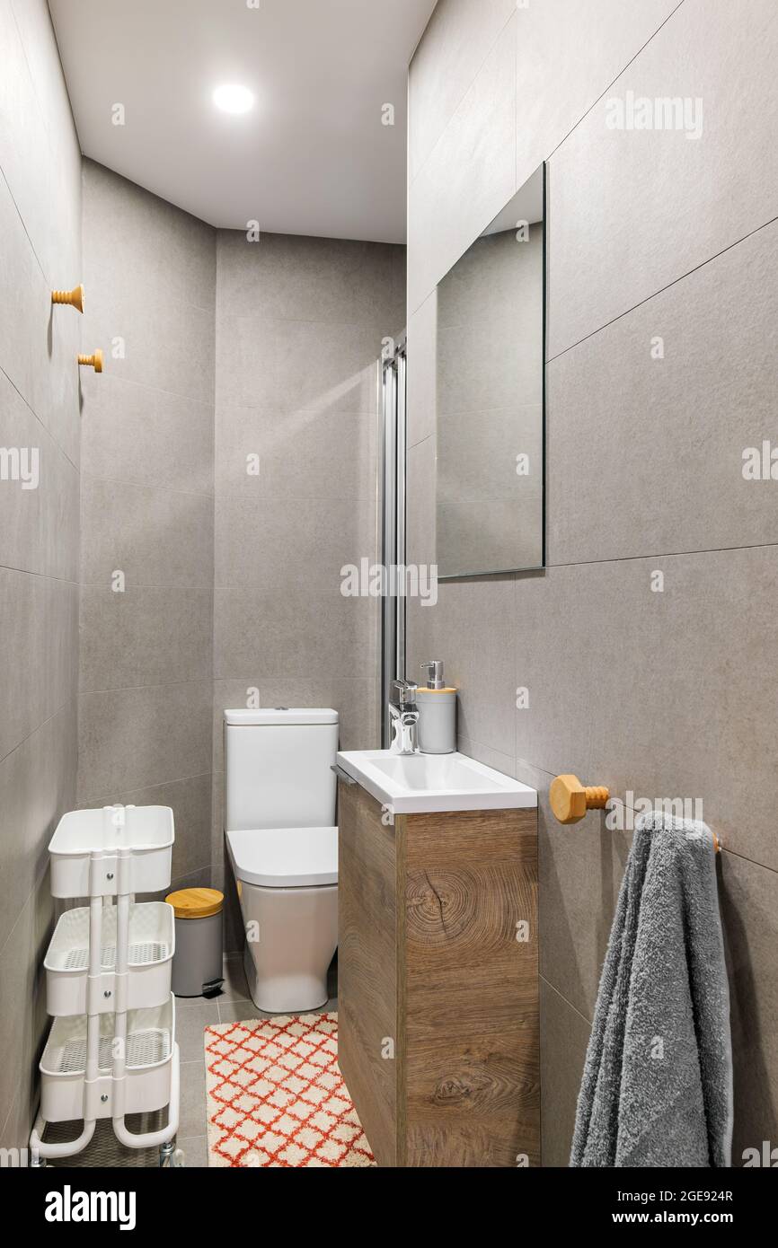 Narrow bathroom with, toilet, small washbasin, decorated with gray tiles.  Contemporary style interior after home renovation Stock Photo - Alamy