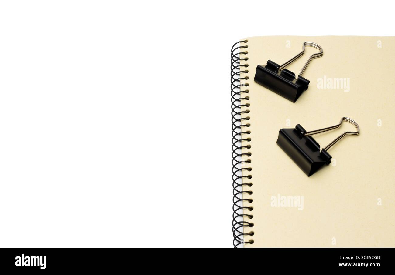 Two black metal binder paper clips on a notebook with white space Stock