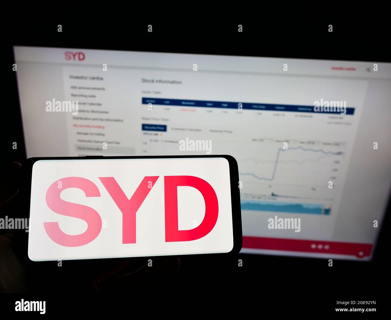 Person holding mobile phone with logo of Australian company Sydney Airport Holdings Pty Ltd on screen in front of web page. Focus on phone display. Stock Photo