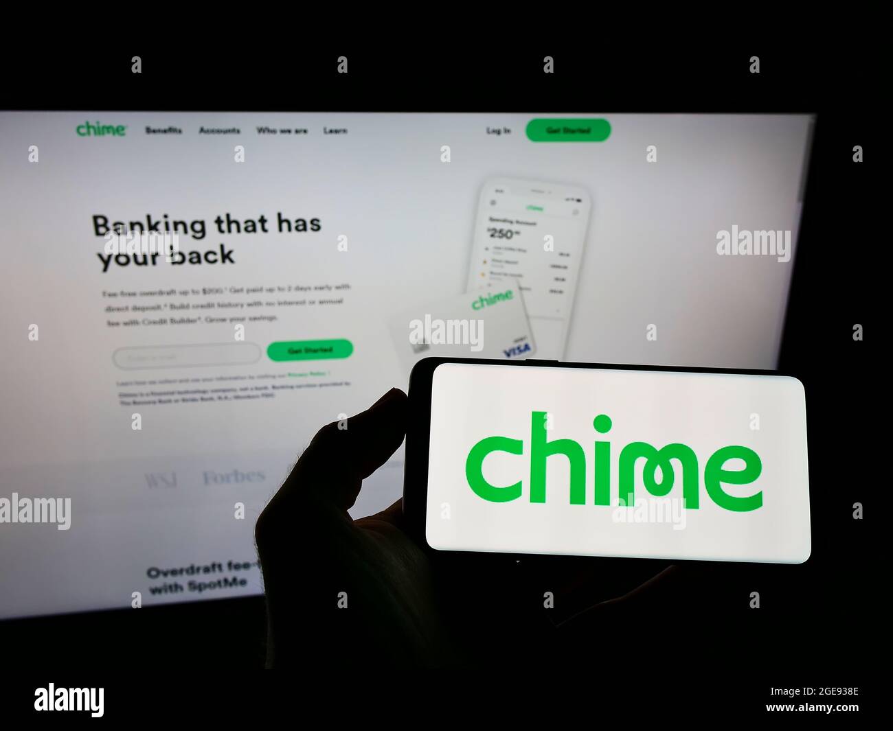Person holding smartphone with logo of US fintech company Chime Financial Inc. on screen in front of website. Focus on phone display. Stock Photo