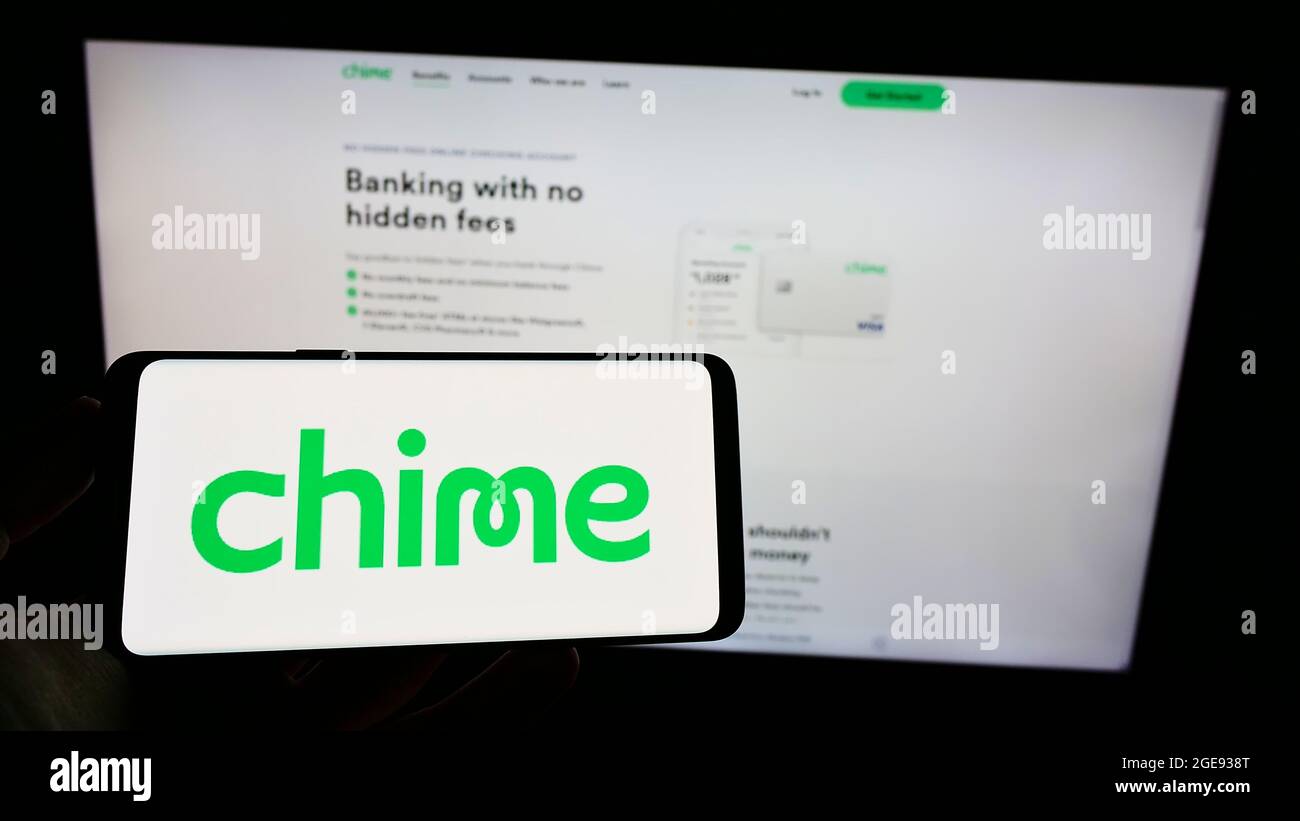 Person holding cellphone with logo of American fintech company Chime Financial Inc. on screen in front of business webpage. Focus on phone display. Stock Photo