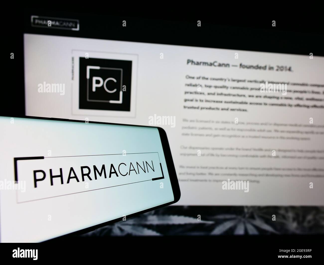 Cellphone with logo of US cannabis company PharmaCann Inc. on screen in front of business website. Focus on center-right of phone display. Stock Photo