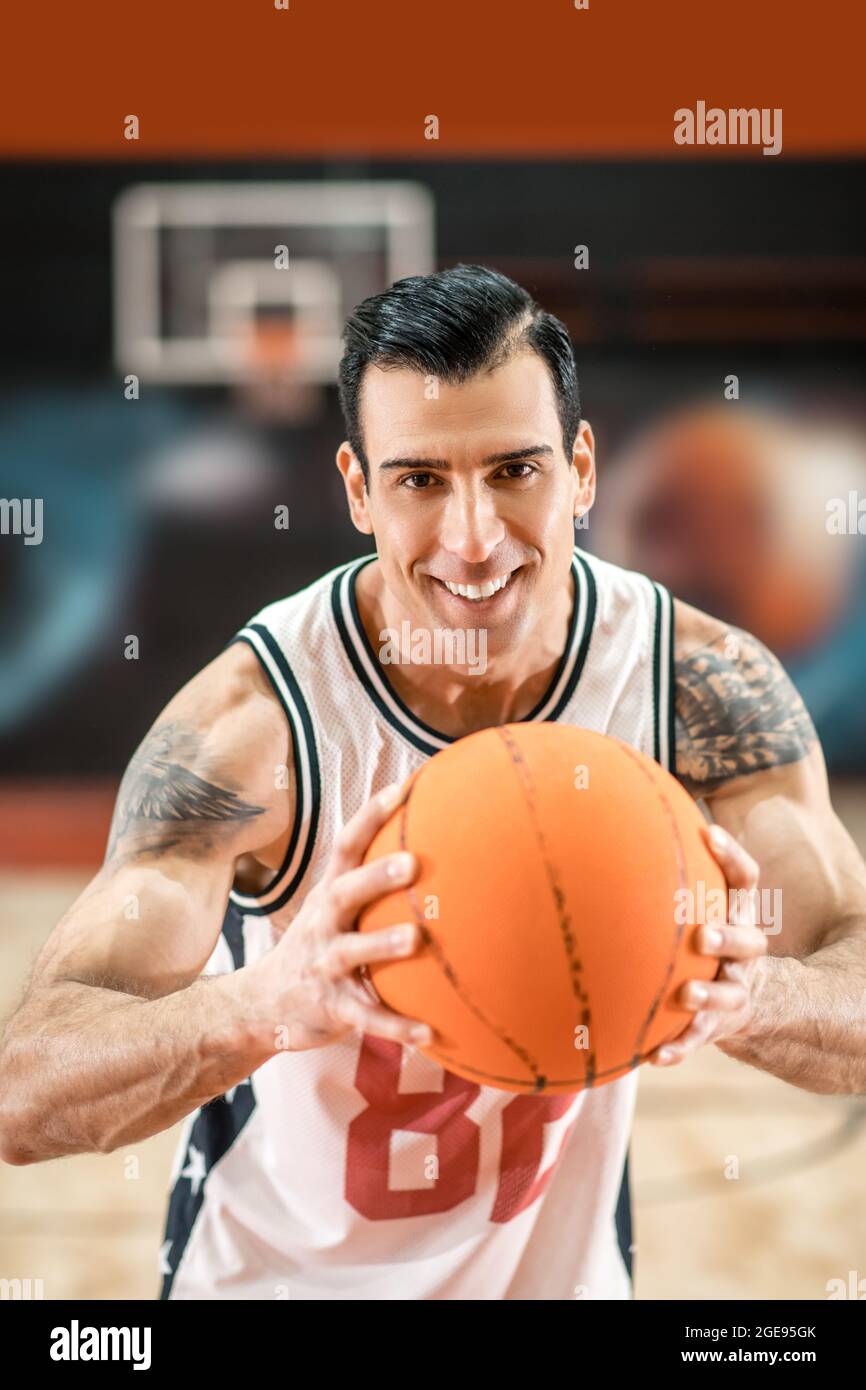handsome sportsman holding a big orange ball in hands Stock
